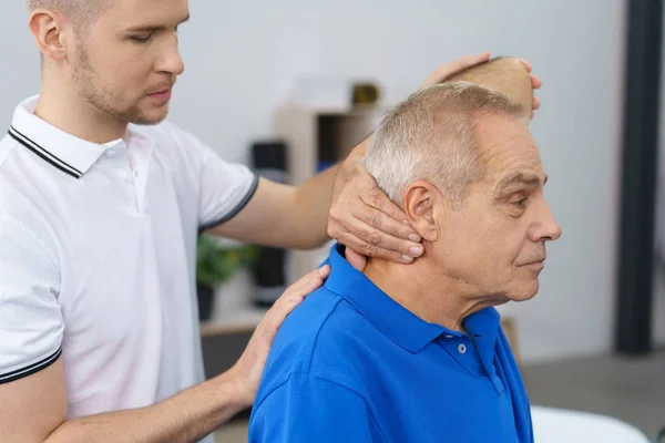Terapista che esamina la schiena di un uomo anziano — Foto Stock