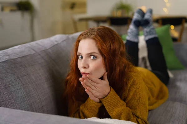 Surprised redhead woman on sofa — Stock Photo, Image