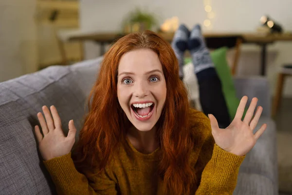 Mujer acostada en el sofá levantando las manos sorprendida — Foto de Stock