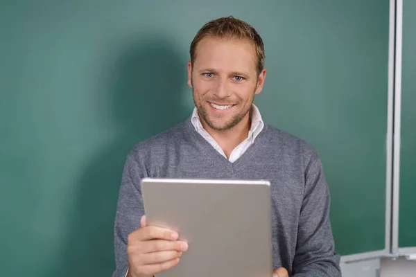 Teacher in front of a chalkboard browsing on a tablet — Stock Photo, Image