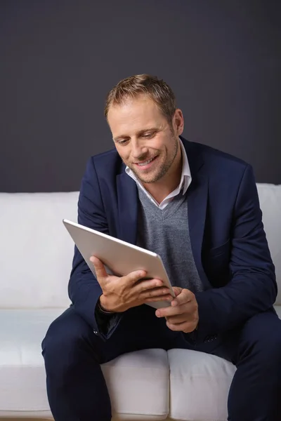 Schöner Mann sitzt beim Lesen auf einem Tablet-Computer — Stockfoto