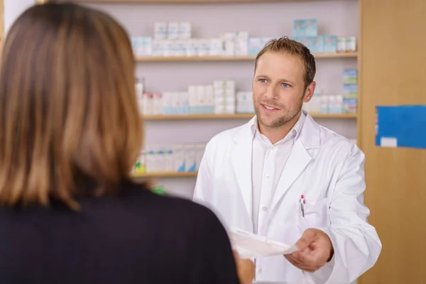 Attractive male pharmacist serving a customer — Stock Photo, Image