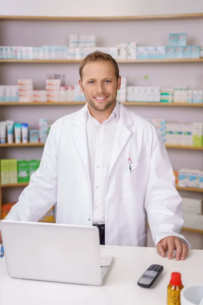 Улыбающийся уверенный мужчина-фармацевт в аптеке — стоковое фото