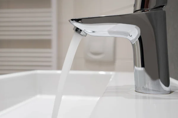 Acqua che scorre da un moderno rubinetto cromato — Foto Stock