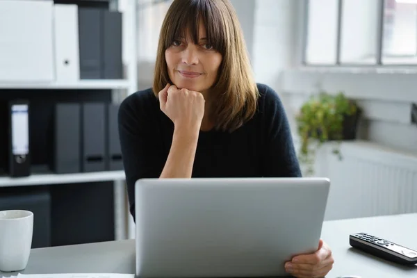 Thoughtful business woman in office with laptop — Stock Photo, Image