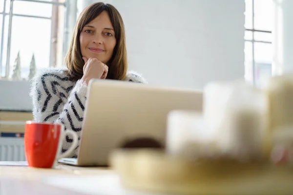 Vriendelijke vrouw die op haar laptop thuis werkt — Stockfoto