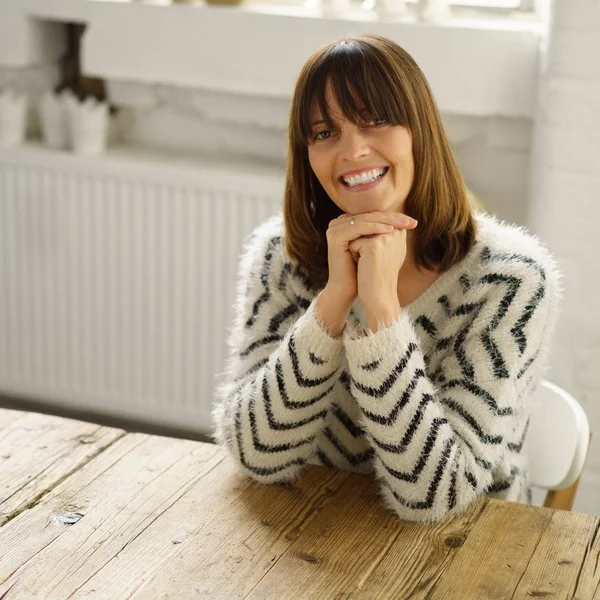 Pretty friendly woman sitting at a wooden table — Stock Photo, Image