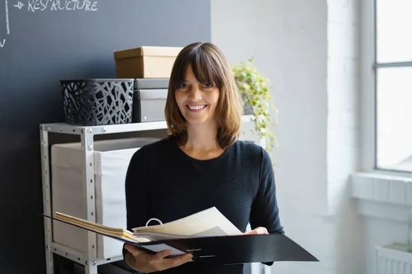 Mujer de negocios sonriente sosteniendo una carpeta abierta — Foto de Stock