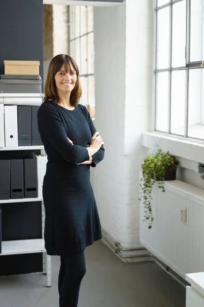 Friendly businesswoman standing with folded arms — Stock Photo, Image