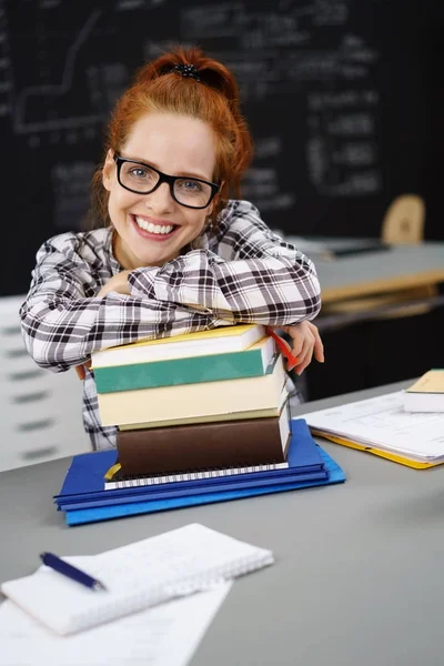 Redhead met glazen berust op een stapel boeken — Stockfoto