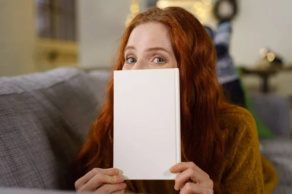 Ginger woman peeping over notepad — Stock Photo, Image
