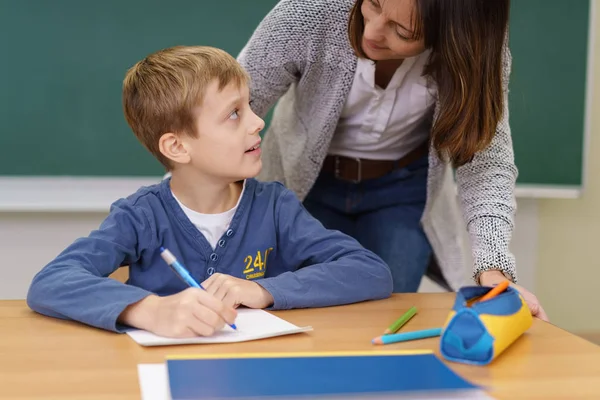 Teacher helping a young boy in class at school — Stock Photo, Image