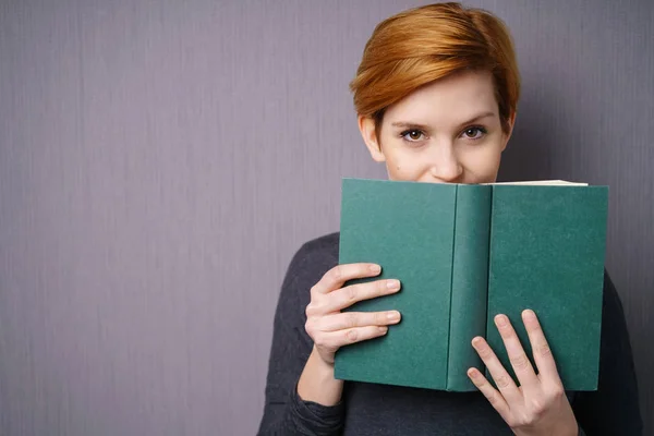 Donna che copre bocca con libro — Foto Stock