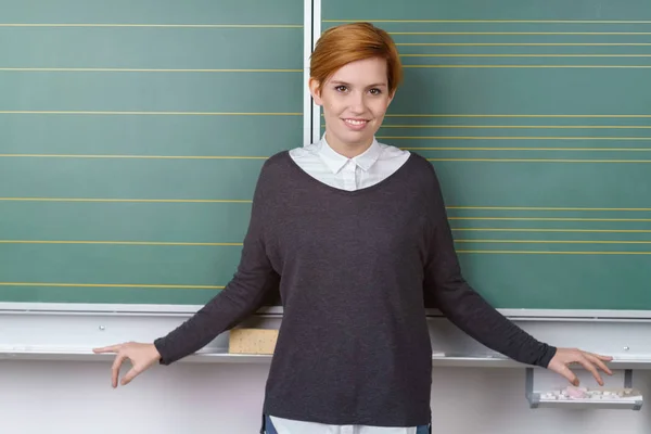 Junge Lehrerin stützt sich auf Kreidetafel — Stockfoto