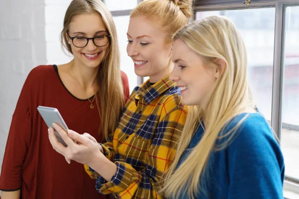 women friends sharing mobile phone