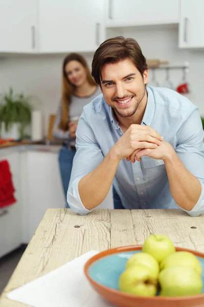 Uśmiechnięty mężczyzna młody siedzi w kuchni — Zdjęcie stockowe