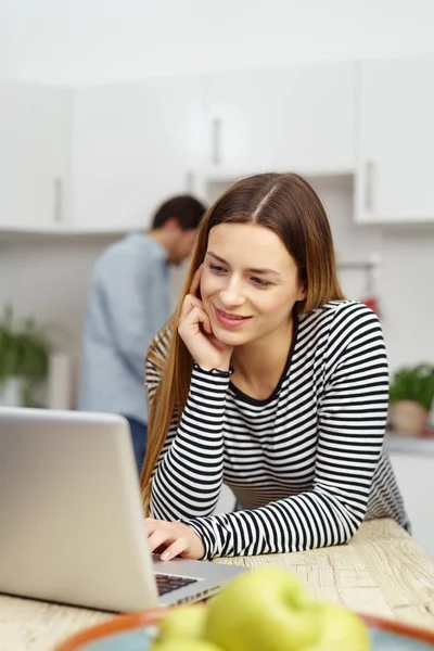 Wanita muda tersenyum dan bekerja dengan laptop — Stok Foto