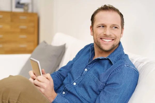 Mand, der bruger smartphone på sofaen - Stock-foto