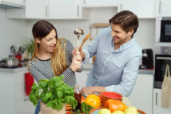 Zábava pár vysmívat, boj s kuchyňským nádobím — Stock fotografie
