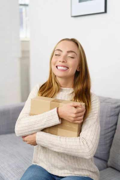Ecstatic young woman hugging a parcel — Stock Photo, Image