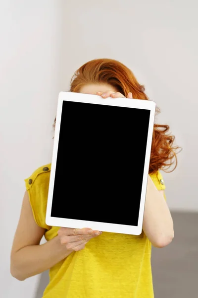 Junge rothaarige Frau hält eine Tablette hoch — Stockfoto