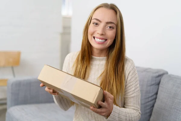 Happy friendly woman holding a brown box — Stock Photo, Image