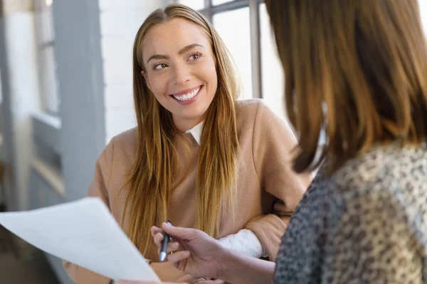 Frau lächelt, als ein Kollege um eine Unterschrift bittet — Stockfoto