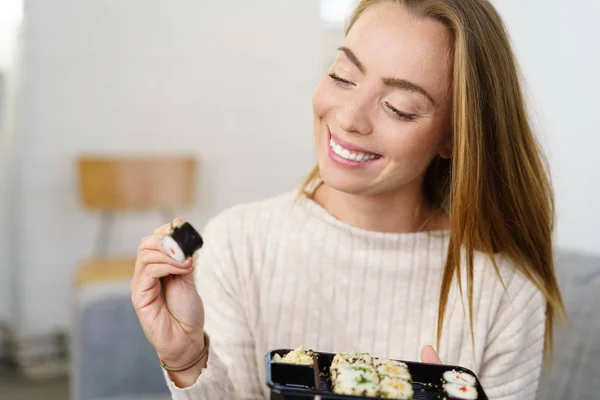 Mujer joven feliz mirando un pedazo de sushi — Foto de Stock