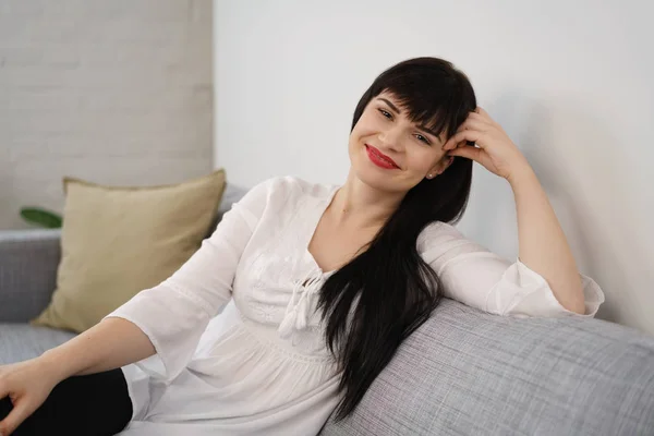 Anmutige junge Frau entspannt sich auf einem Sofa — Stockfoto