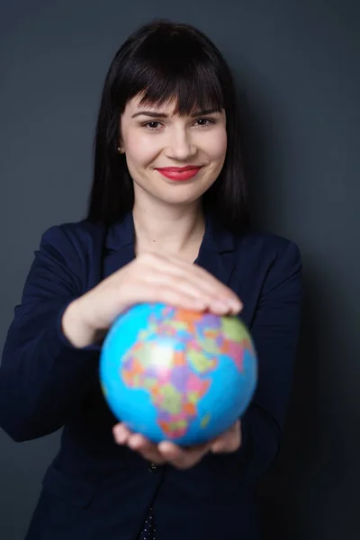 Sorrindo mulher amigável segurando um globo mundial — Fotografia de Stock