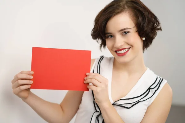 Bir kırmızı kart tutan çekici genç kadın — Stok fotoğraf
