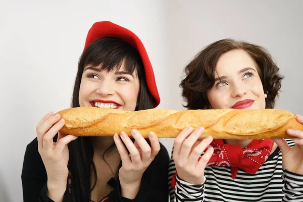 Dos mujeres riendo lindo sosteniendo una baguette — Foto de Stock