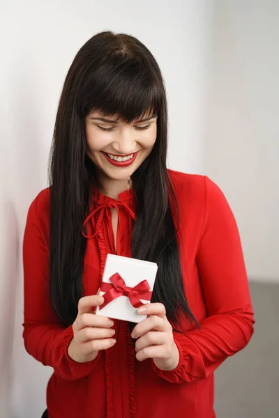 Pretty young woman holding a gift box with a smile — Stock Photo, Image