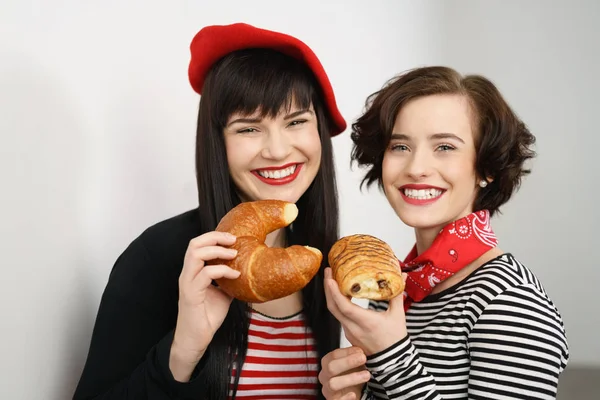 Dos jóvenes felices sosteniendo pasteles franceses — Foto de Stock