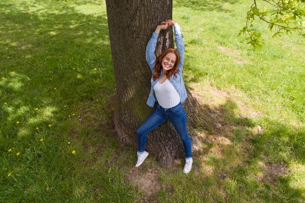 Mutlu genç kadın bir ağaç karşı rahatlatıcı — Stok fotoğraf