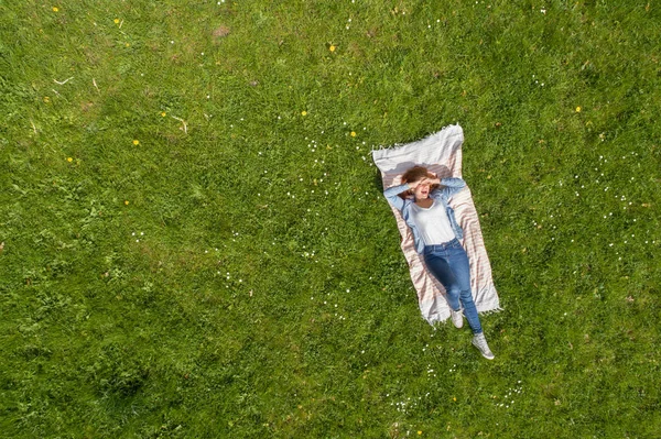 Junge Frau liegt auf einem Teppich im grünen Gras — Stockfoto