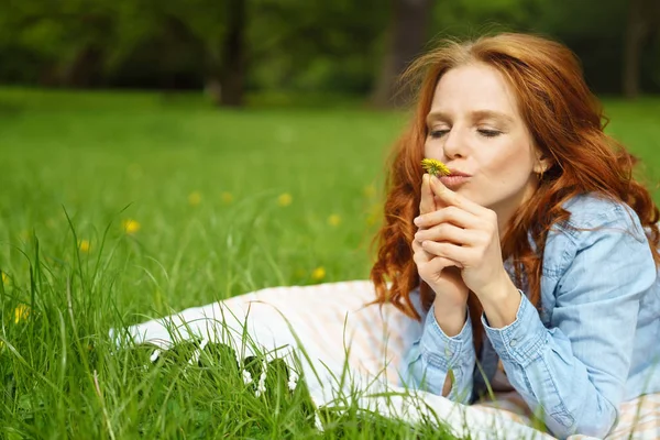 Funny young woman kissing a fresh dandelion — Stock Photo, Image