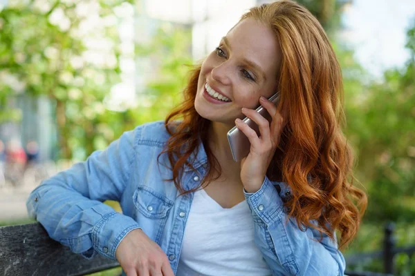 Prachtige jonge roodharige vrouw chatten via een mobiele — Stockfoto