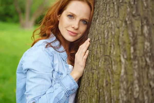 Sérieux réfléchi jeune femme appuyée sur un arbre — Photo