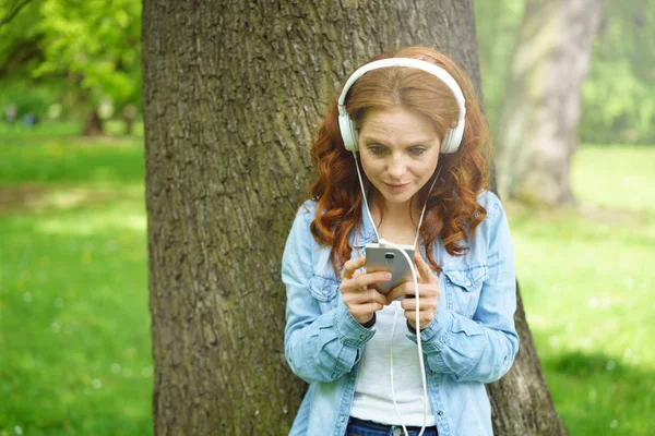 Giovane donna che ascolta musica in un parco — Foto Stock