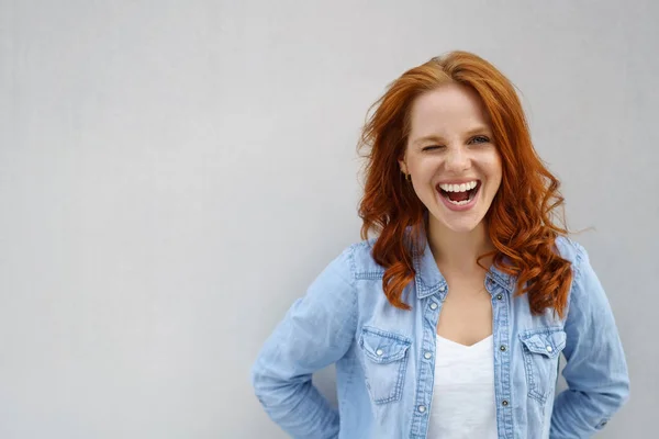 Laughing vivacious woman winking at the camera — Stock Photo, Image