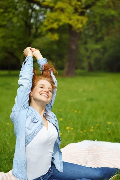 Happy uvolněná mladá žena táhnoucí se v parku — Stock fotografie