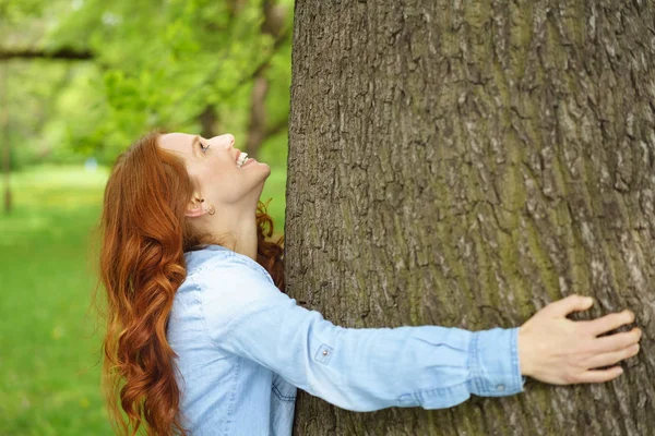 幸福的年轻女人，拥抱一棵树干 — 图库照片