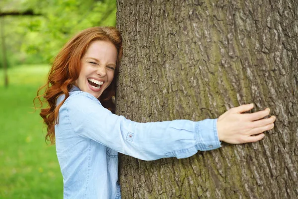 Genç kadın büyük bir ağaç sarılmayı gülüyor — Stok fotoğraf