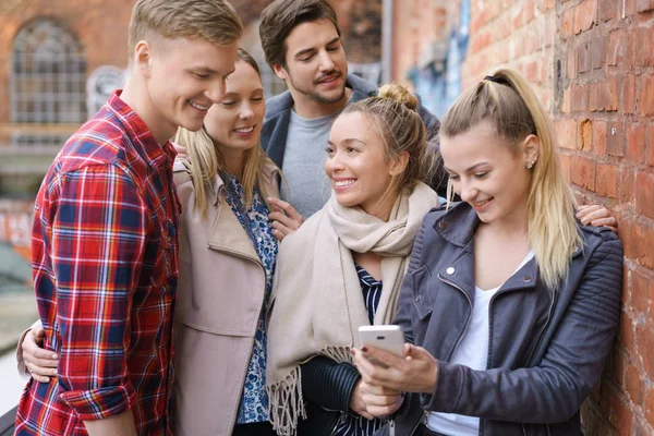 Grupo de amigos universitários olhando para um celular — Fotografia de Stock