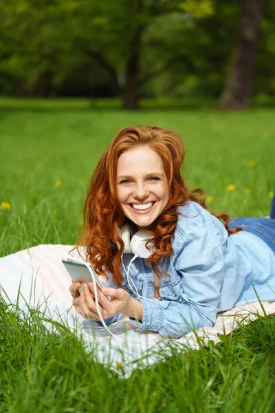 Jolie jeune femme se relaxant sur l'herbe dans un parc — Photo