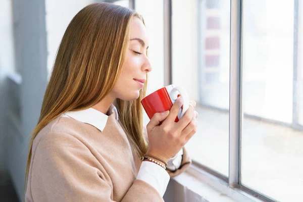 Zalige jonge vrouw die geniet van de geur van koffie — Stockfoto