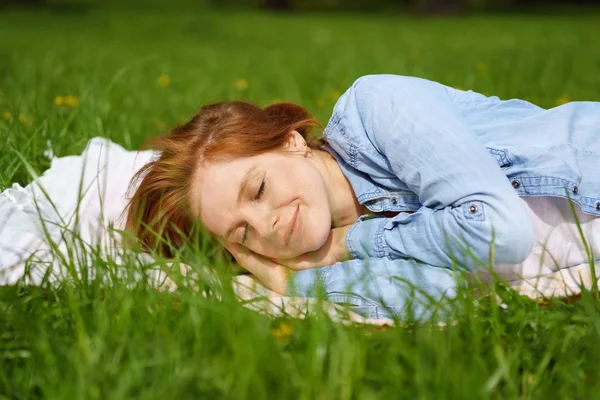 Mooie jonge roodharige vrouw ontspannen op gras — Stockfoto