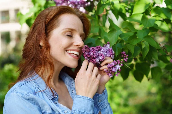 Gelukkig jonge vrouw die geniet van de geur van lila — Stockfoto