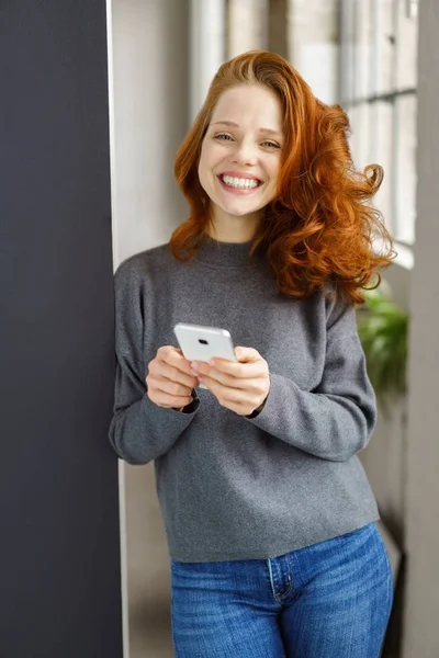 Mujer joven extática sosteniendo un teléfono móvil — Foto de Stock